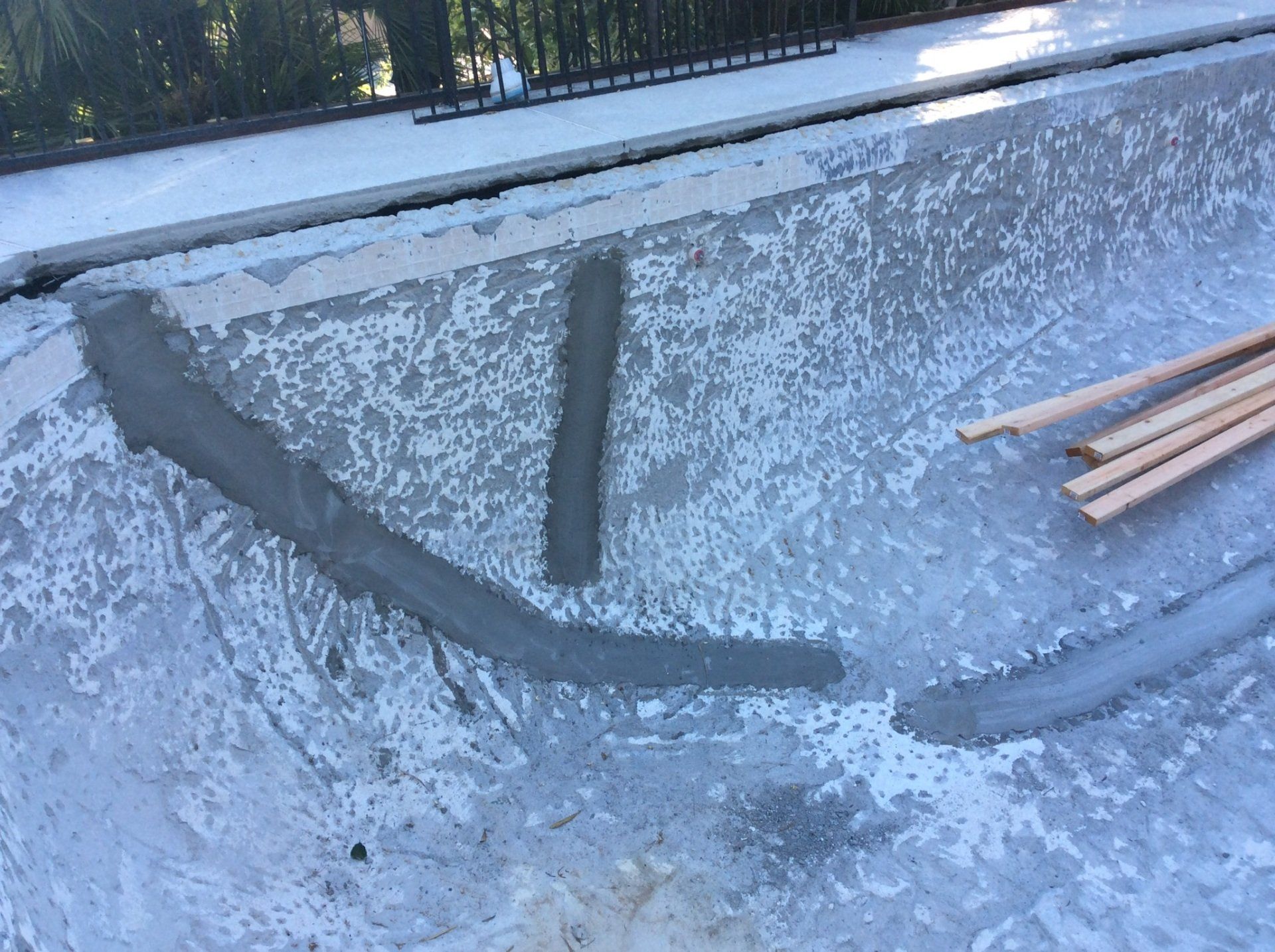A concrete bowl is being built next to a wooden railing.