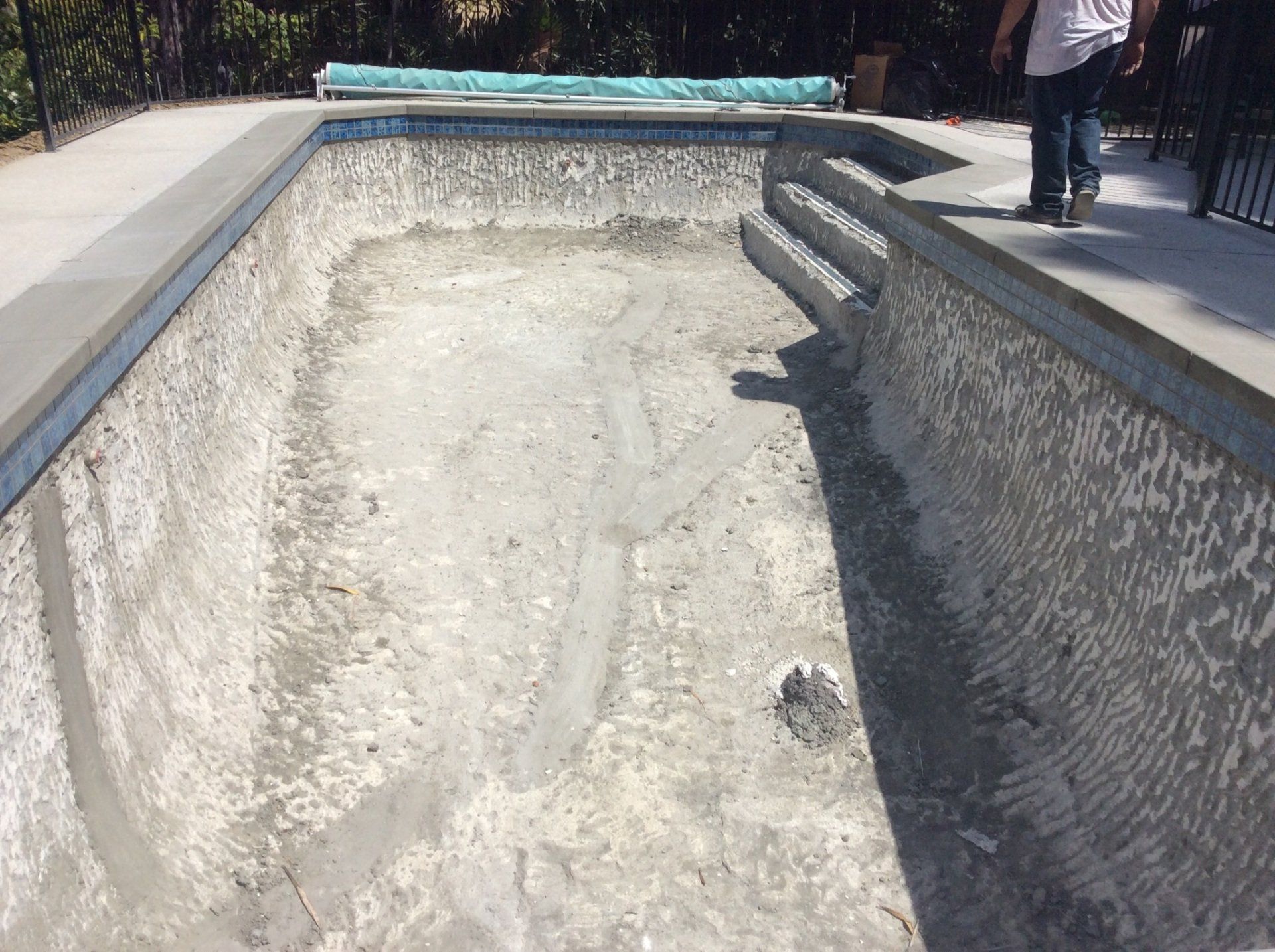 A man is standing next to an empty swimming pool