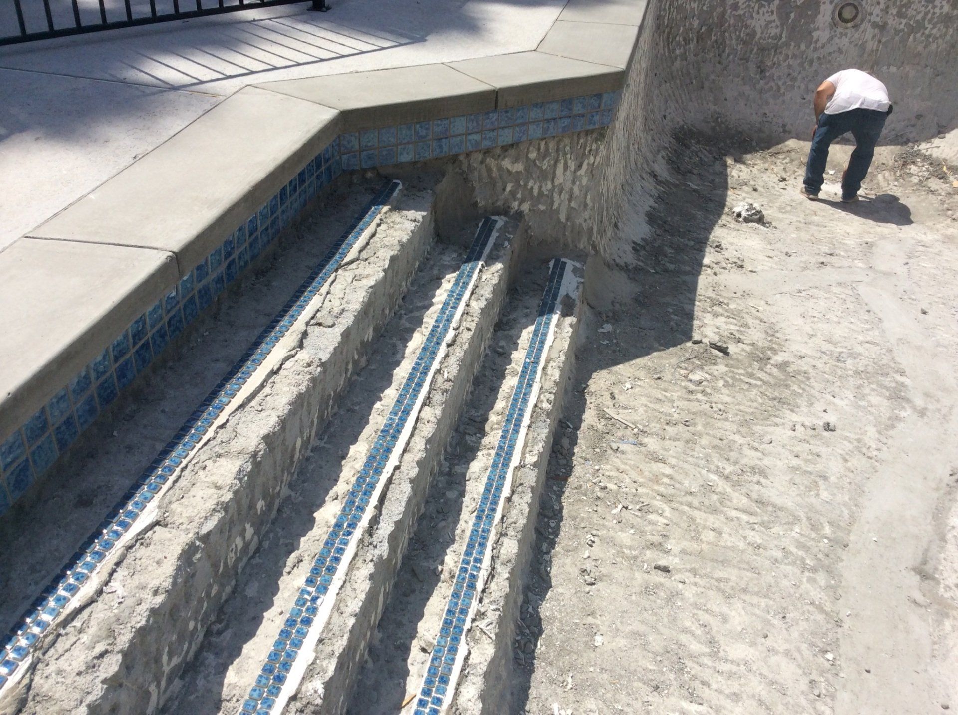 A man is working on the steps of a swimming pool
