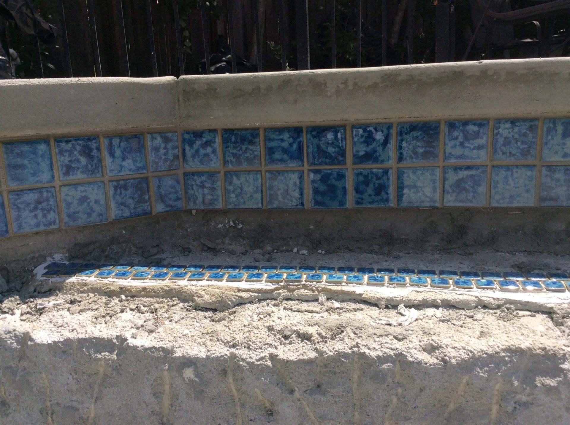 A concrete wall with blue tiles on it.