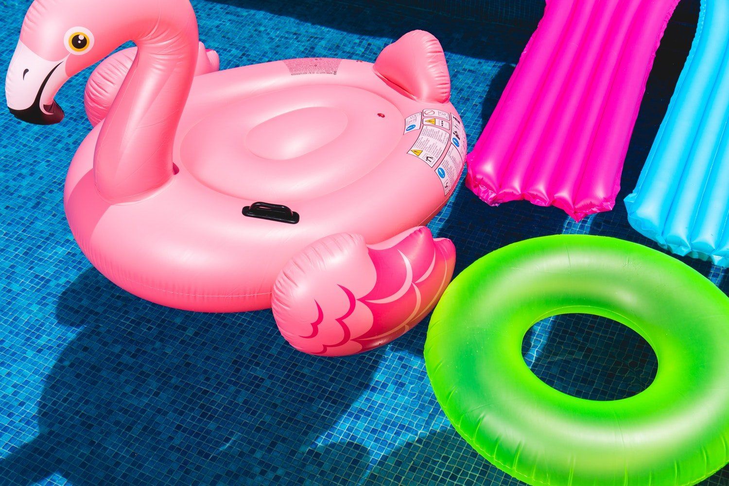 A pink flamingo float is sitting on top of a swimming pool.