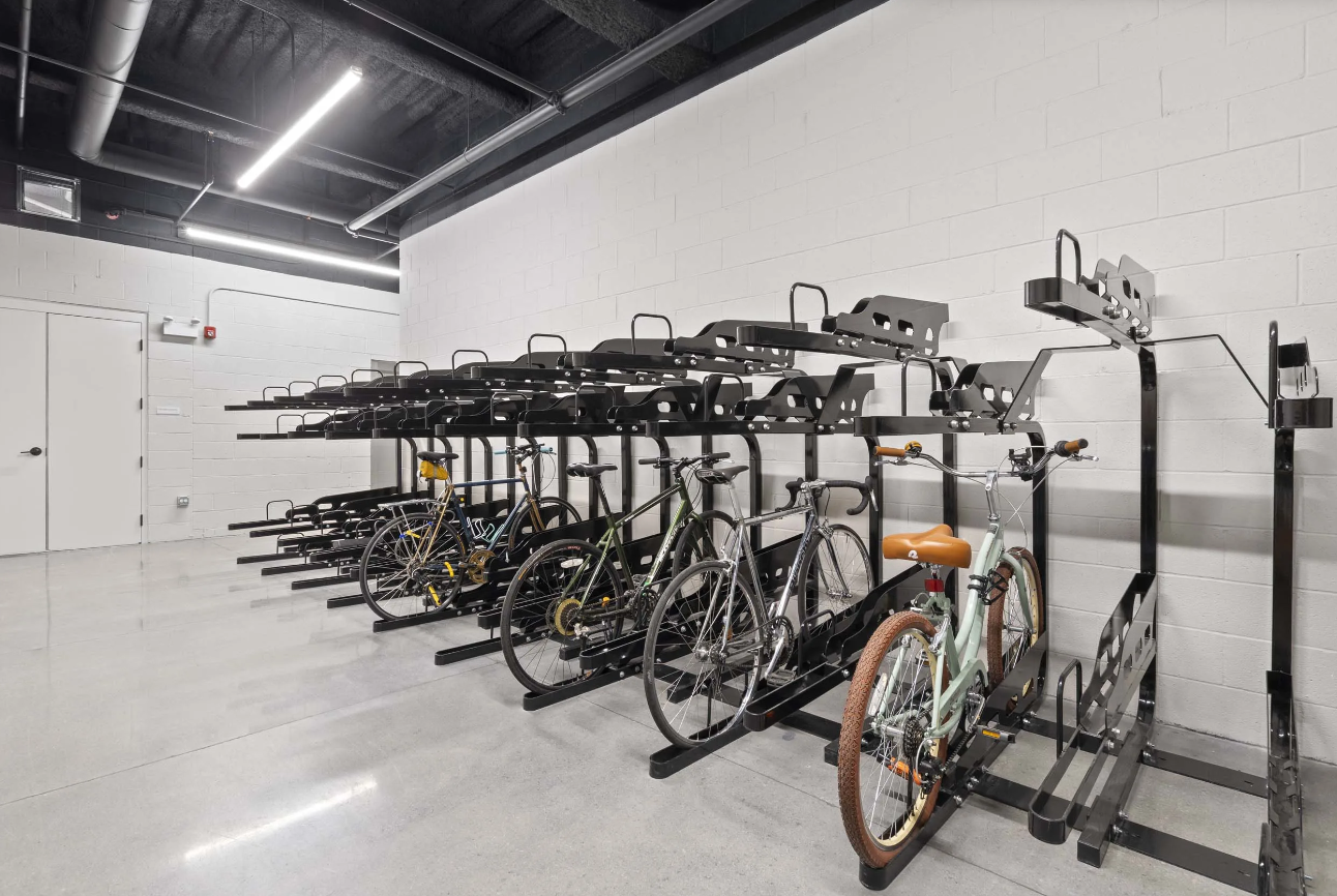Bicycle storage room with several bikes parked on black wall-mounted racks
