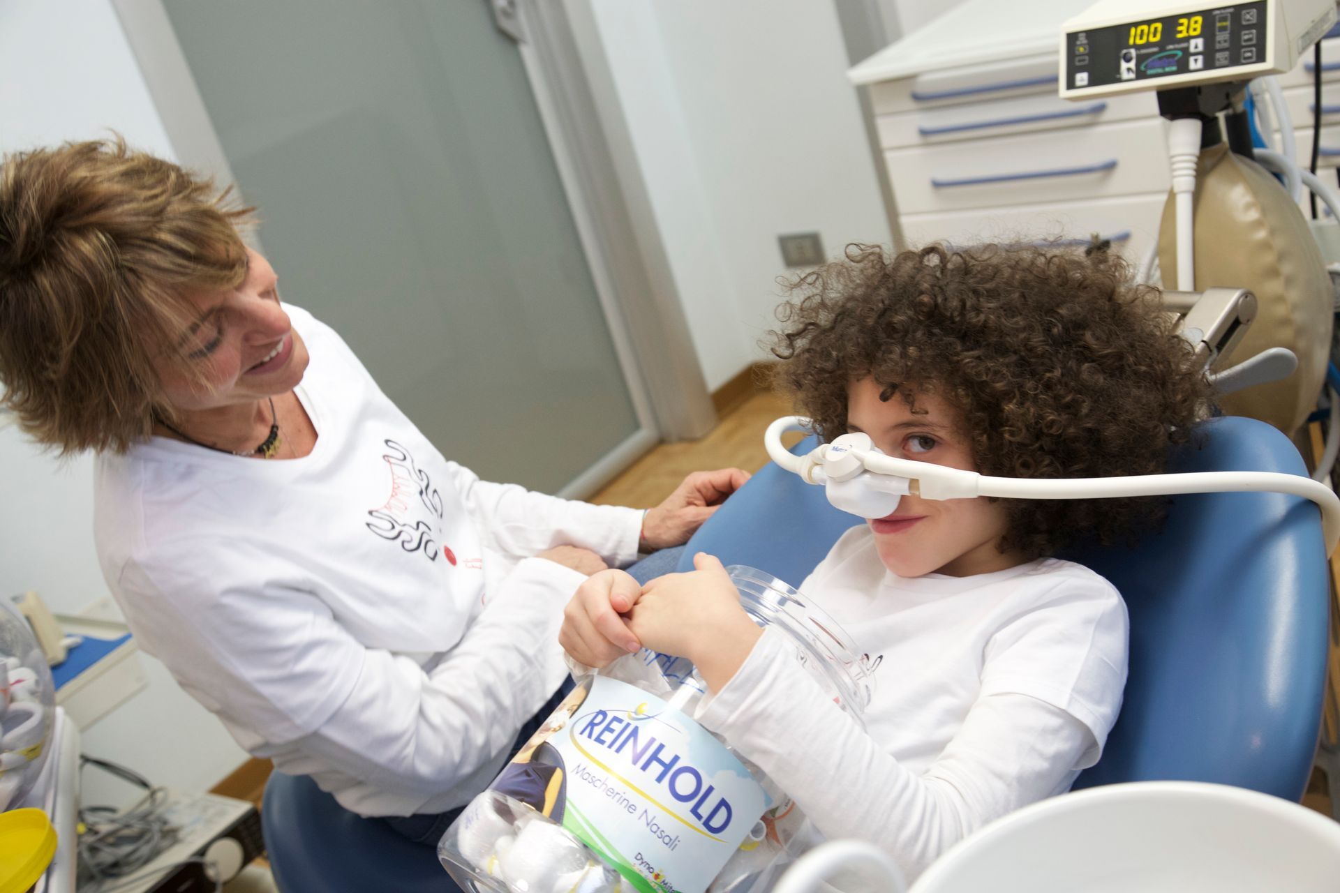 Dentista e bambino che indossano una mascherina durante una visita odontoiatrica in una clinica.