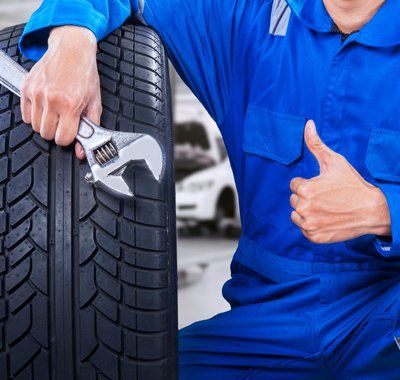 Used Tires — Mechanic Doing Thumbs Up Beside A New Tire In Milwaukee, WI