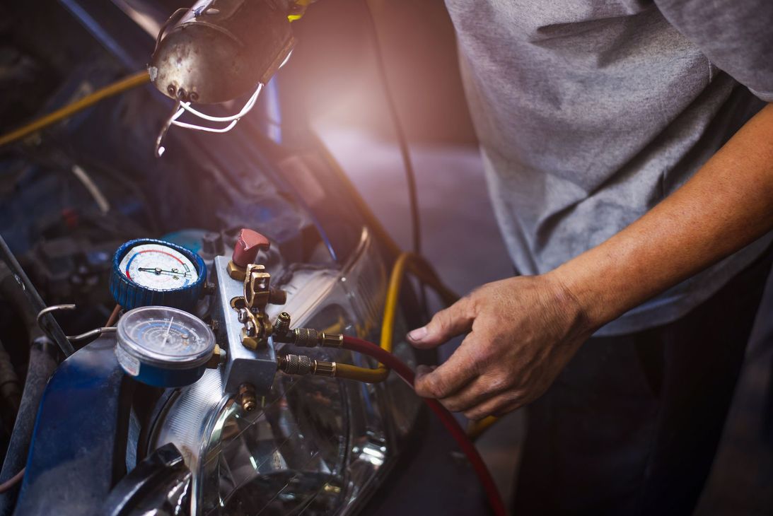 Meccanico che ripara il motore di un'auto, utilizzando indicatori e attrezzi sotto il cofano.