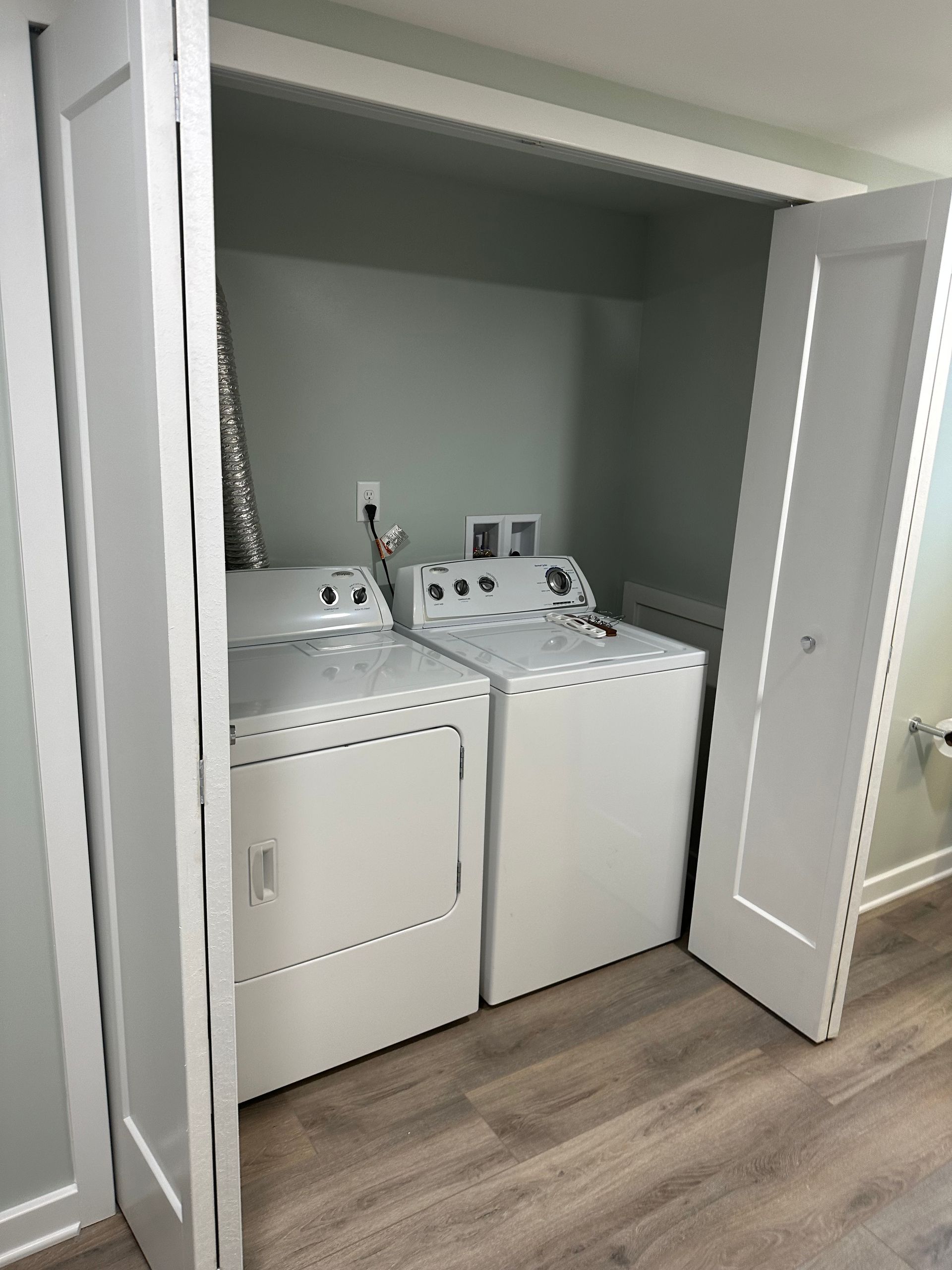 White washer and dryer inside a closet with closed doors and light green walls.
