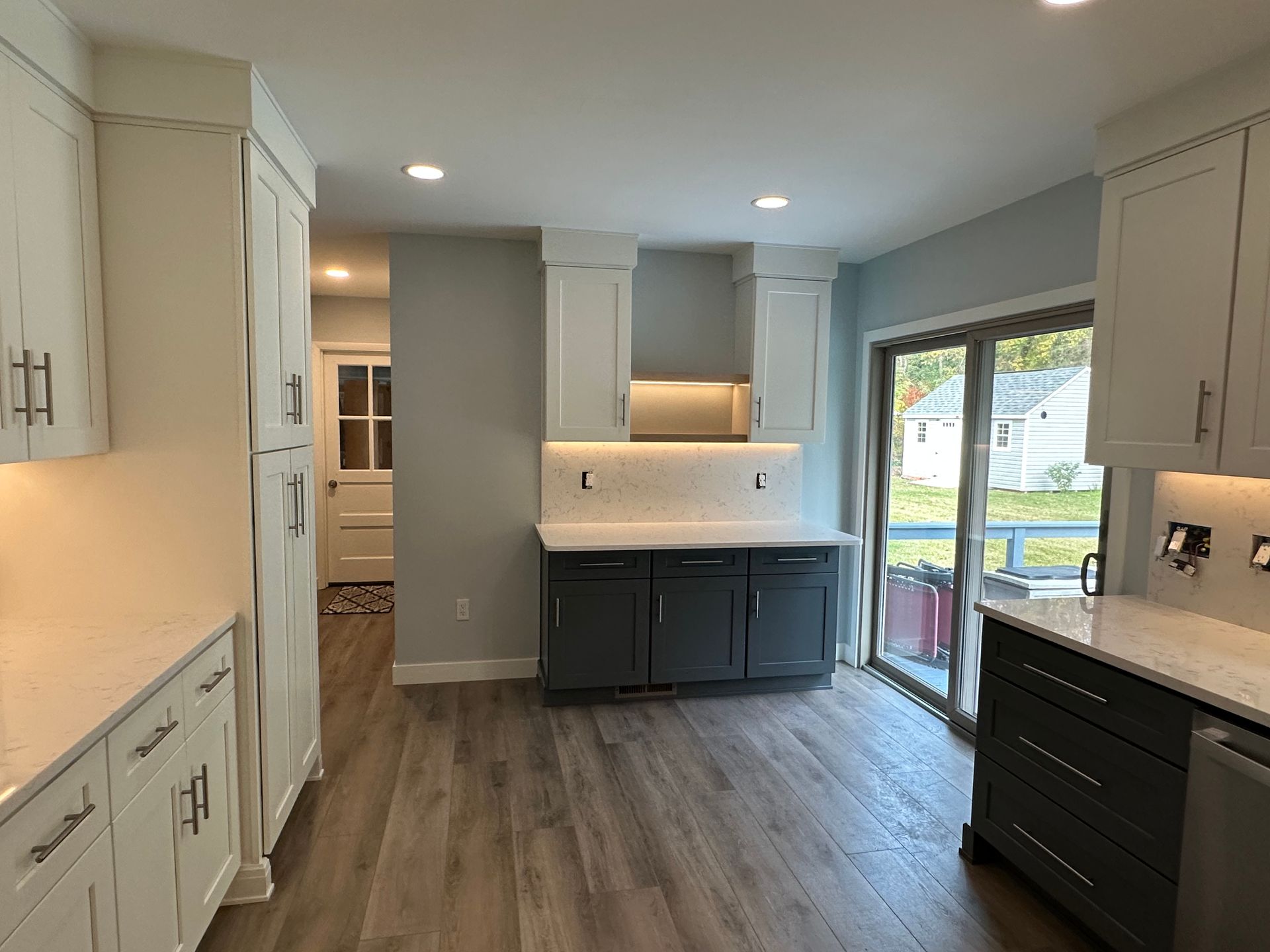 Newly renovated kitchen with white and gray cabinets, light blue walls, and wood-look flooring.
