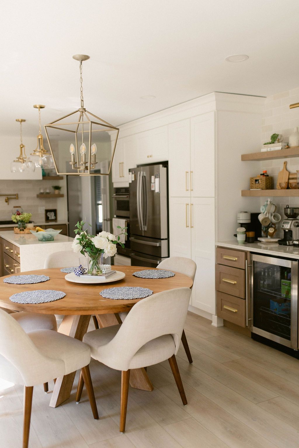 Modern kitchen and dining area with wooden table, cream chairs, and stainless steel appliances.