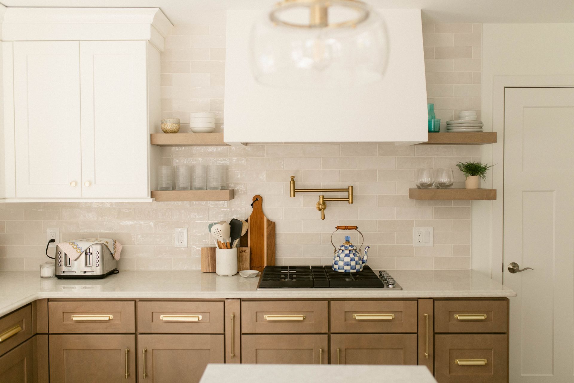 Modern kitchen with white and brown cabinets, stainless steel appliances, and beige tile backsplash.