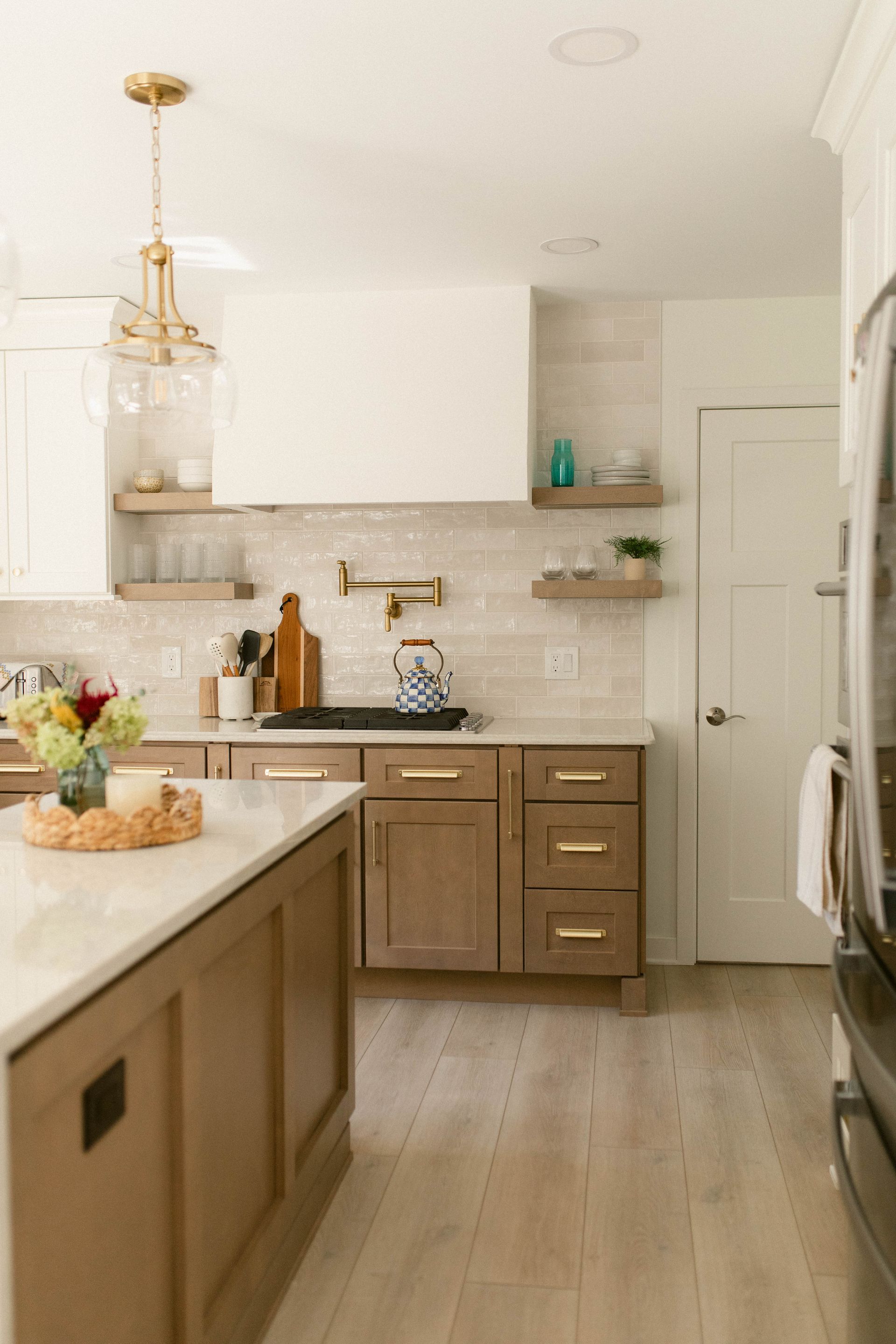 Modern kitchen with wood cabinets, white countertops, and decorative shelves.