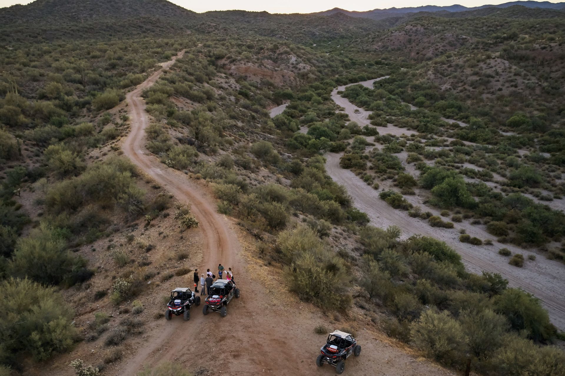 A group of people are riding atvs down a dirt road in the desert.