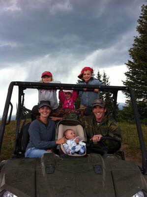 Family in an off-road vehicle: parents, three children, and a baby. Cloudy sky, outdoors.