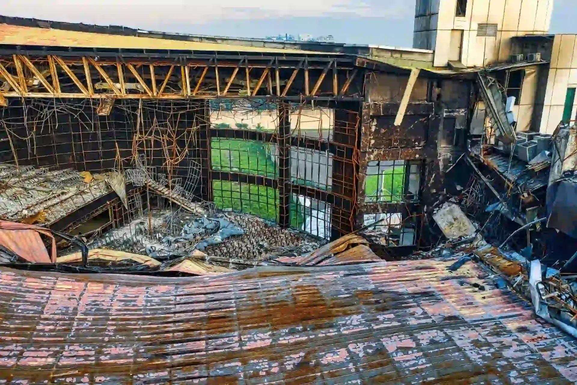 An aerial view of a building interior destroyed by fire, showing exposed metal beams, charred surfaces, and debris.