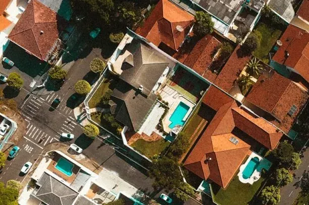 Aerial view of a residential neighborhood with several houses featuring orange roofs and backyard swimming pools.