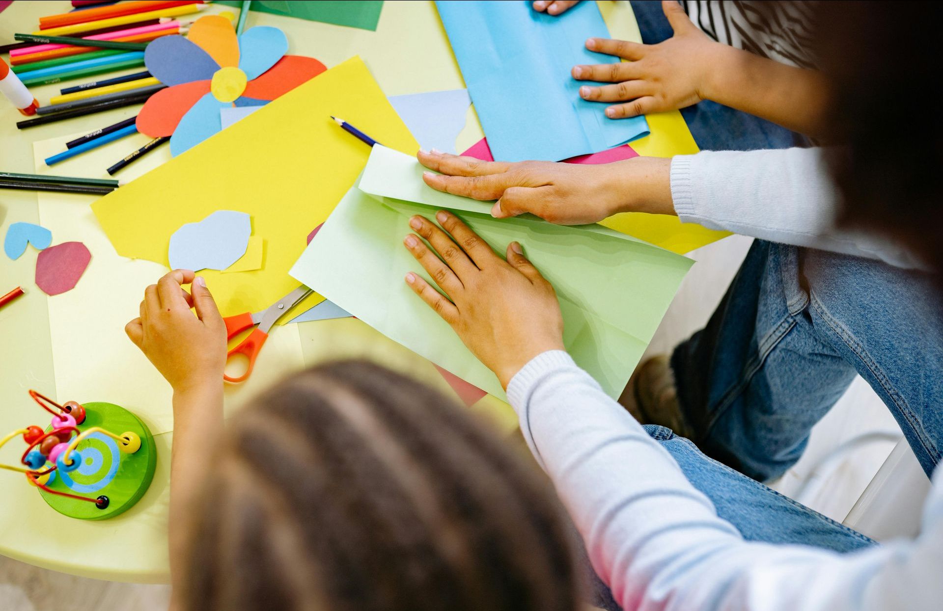 Group of kids working on a craft project, using bright, colorful paper.