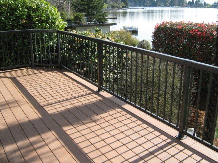 Deck with brown planks and black railing overlooking a lake.