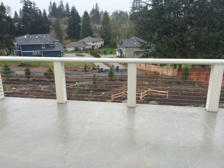 View from a deck of houses, a freshly tilled yard, and trees on an overcast day.