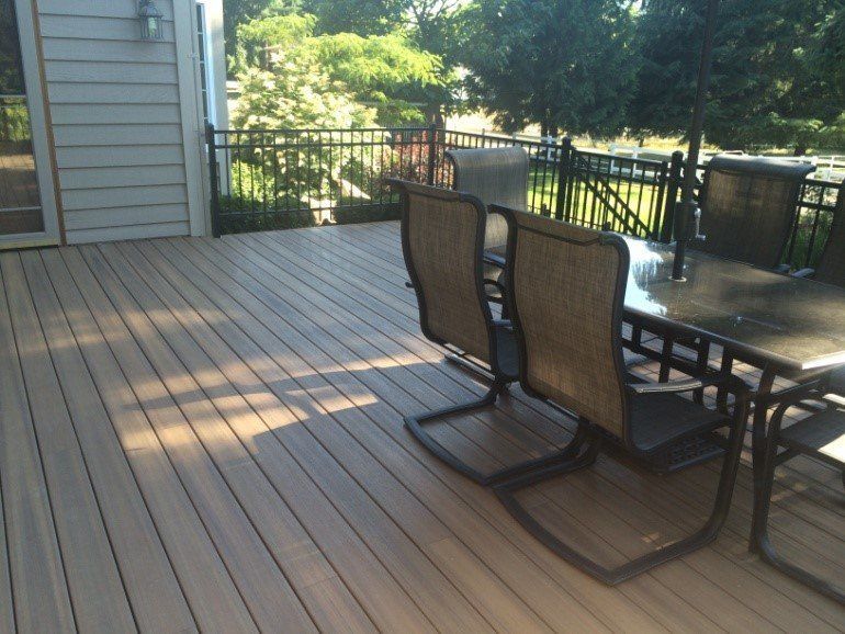 Outdoor deck with patio furniture, overlooking a backyard with trees.