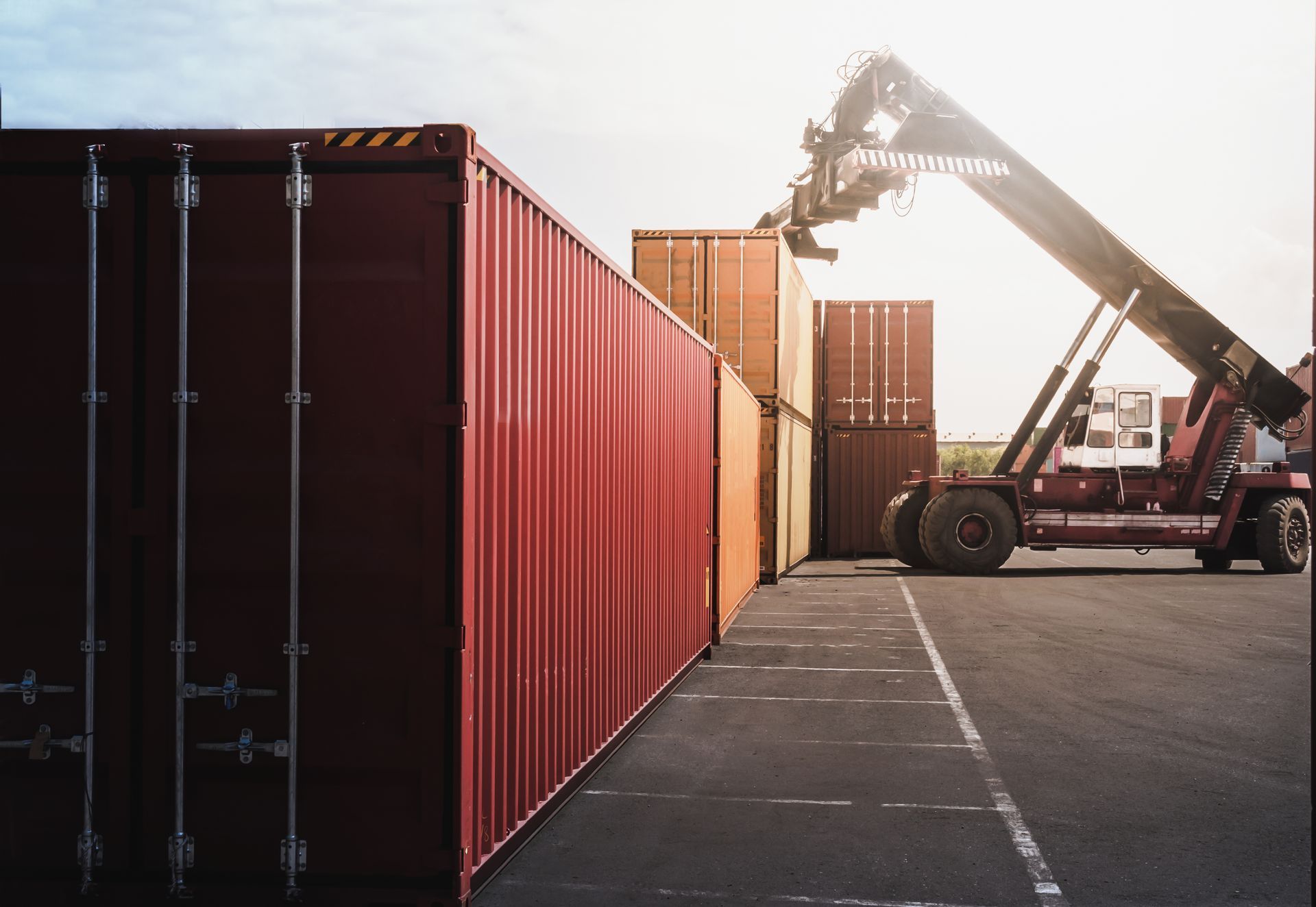 A crane is lifting a container in a parking lot.