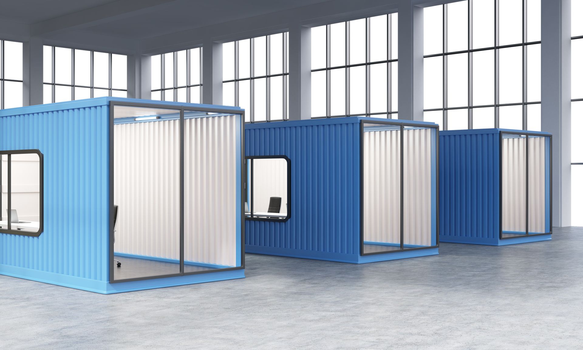 A row of blue shipping containers in a warehouse with windows.