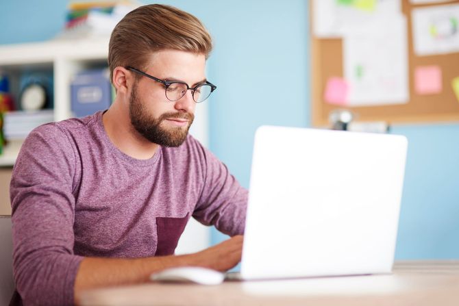 A man is sitting at a desk using a laptop computer.