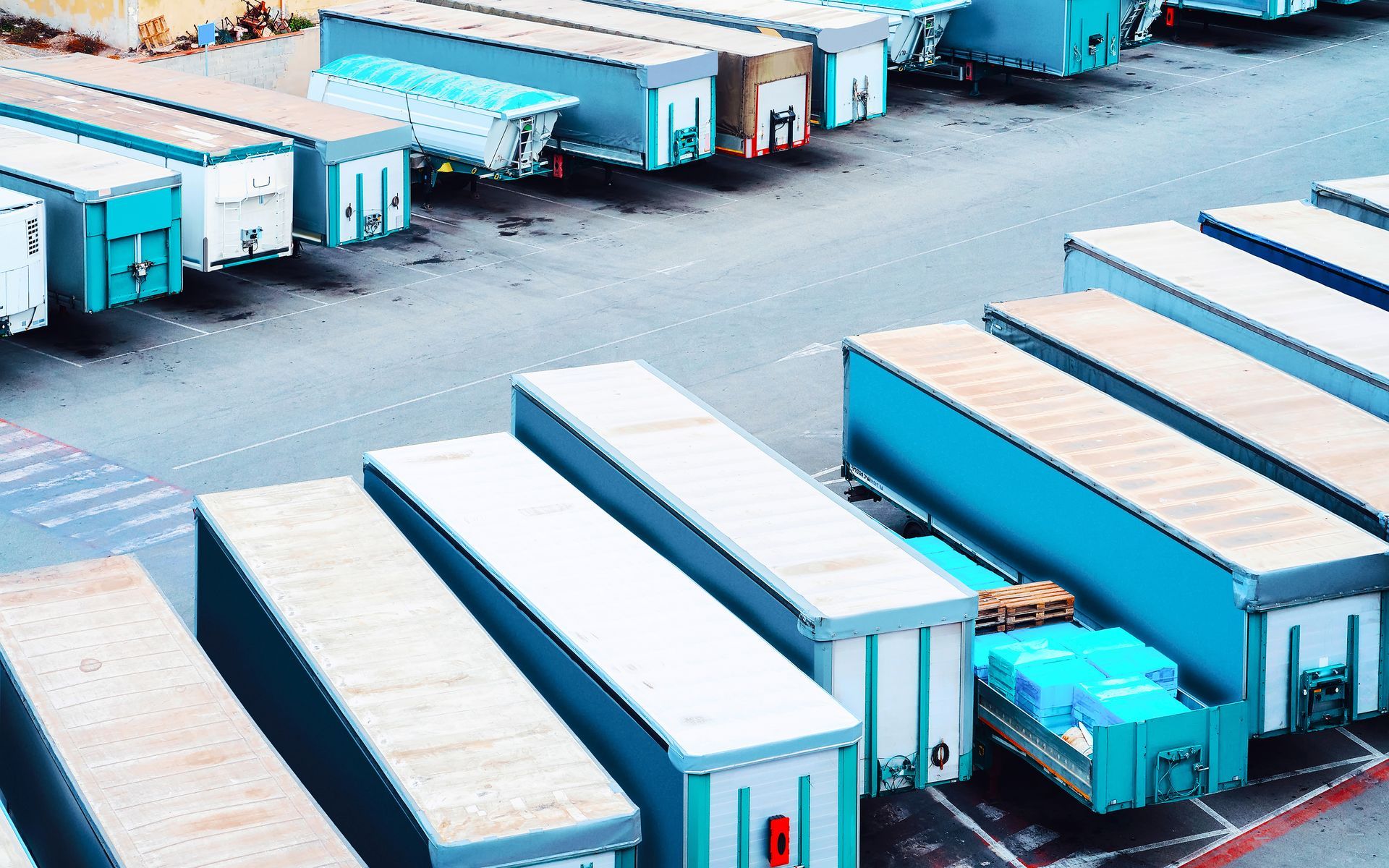 A row of shipping containers are lined up in a parking lot.