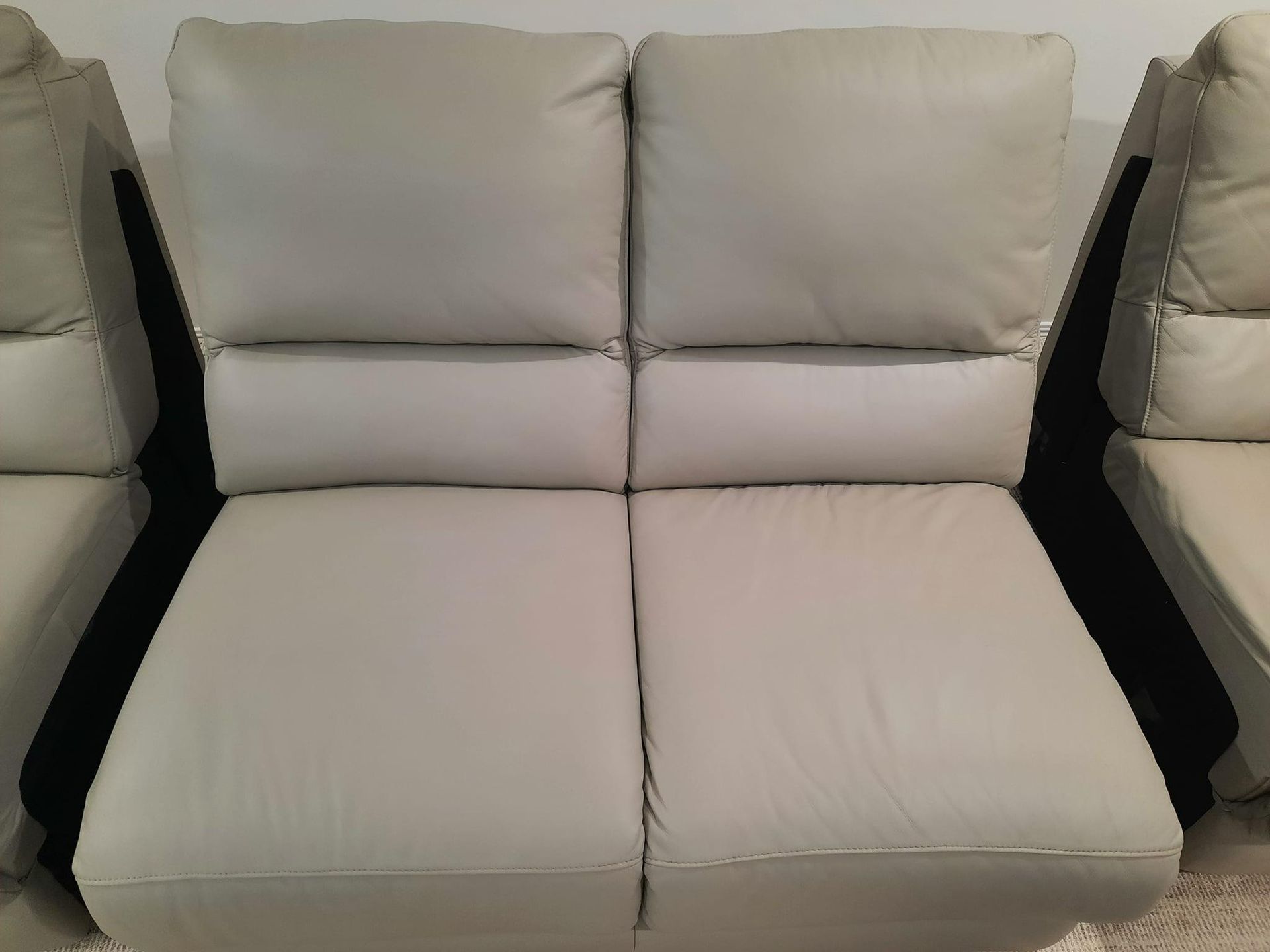 A White Leather Couch With Black Arm Rests and Pillows — Abbsolve Services in Caloundra, QLD