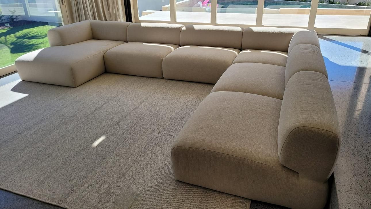 A Large Sectional Couch is Sitting on a Rug in a Living Room — Abbsolve Services in Gympie, QLD