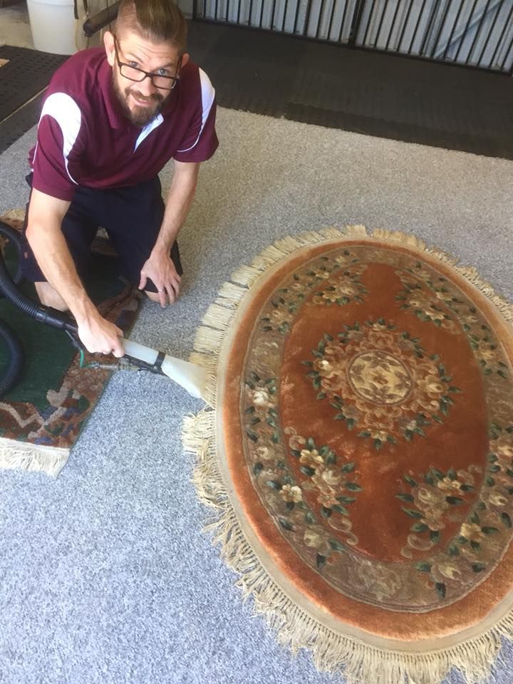 A Man is Cleaning a Rug With a Vacuum Cleaner — Abbsolve Services in Cooroy, QLD