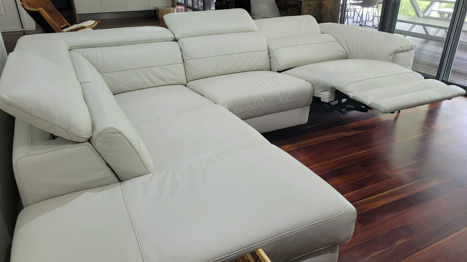 A White Leather Sectional Couch is Sitting on a Wooden Floor in a Living Room — Abbsolve Services in Noosa, QLD