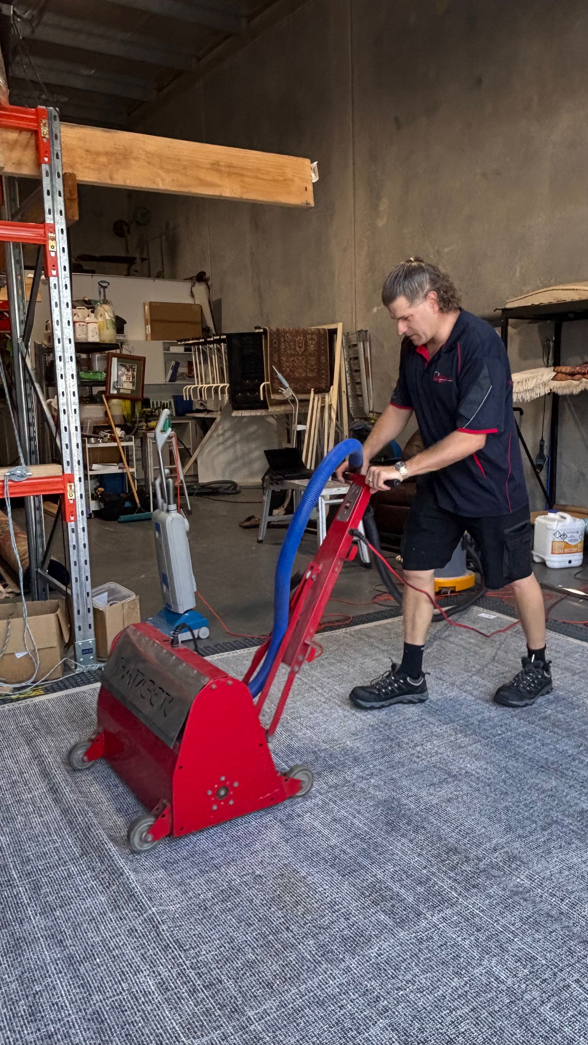 A Man is Cleaning a Rug With a Vacuum Cleaner — Abbsolve Services in Cooroy, QLD