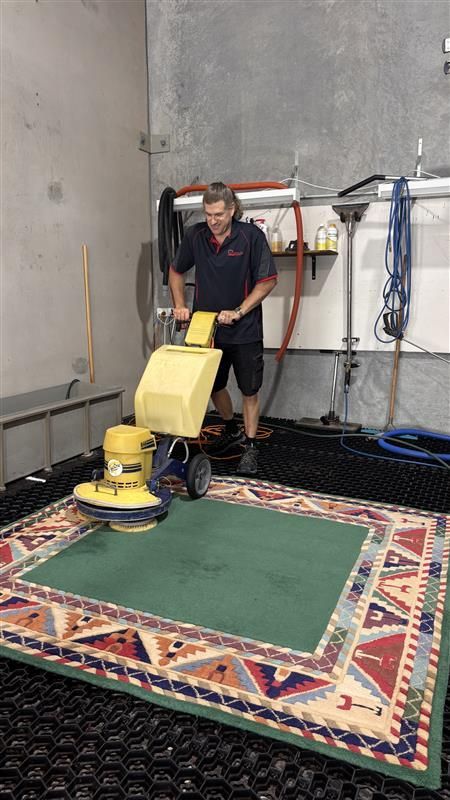 A Man is Sitting on the Floor Painting a White Leather Couch — Abbsolve Services in Peregian Beach, QLD