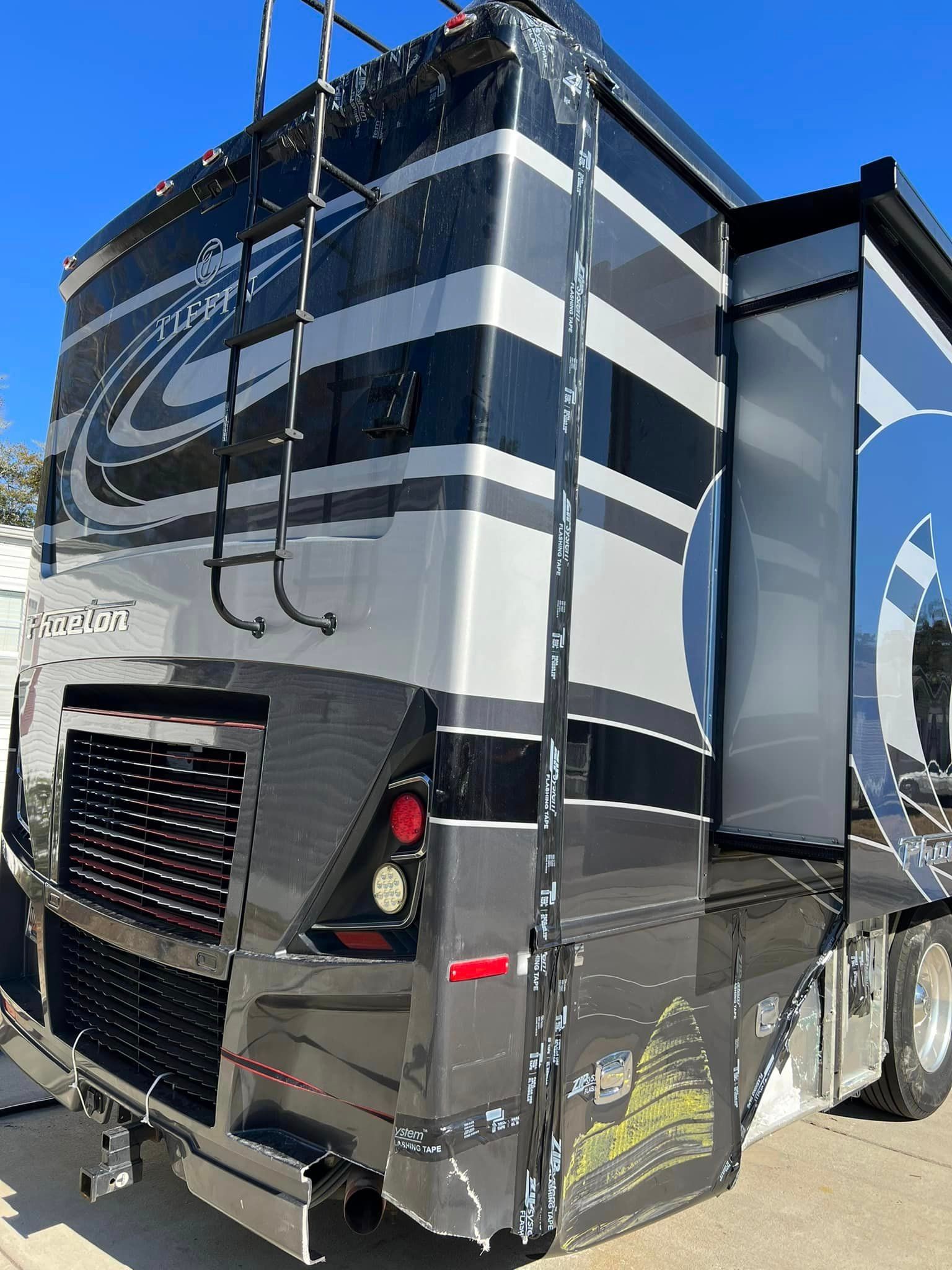 A large gray and white rv is parked on the side of the road.