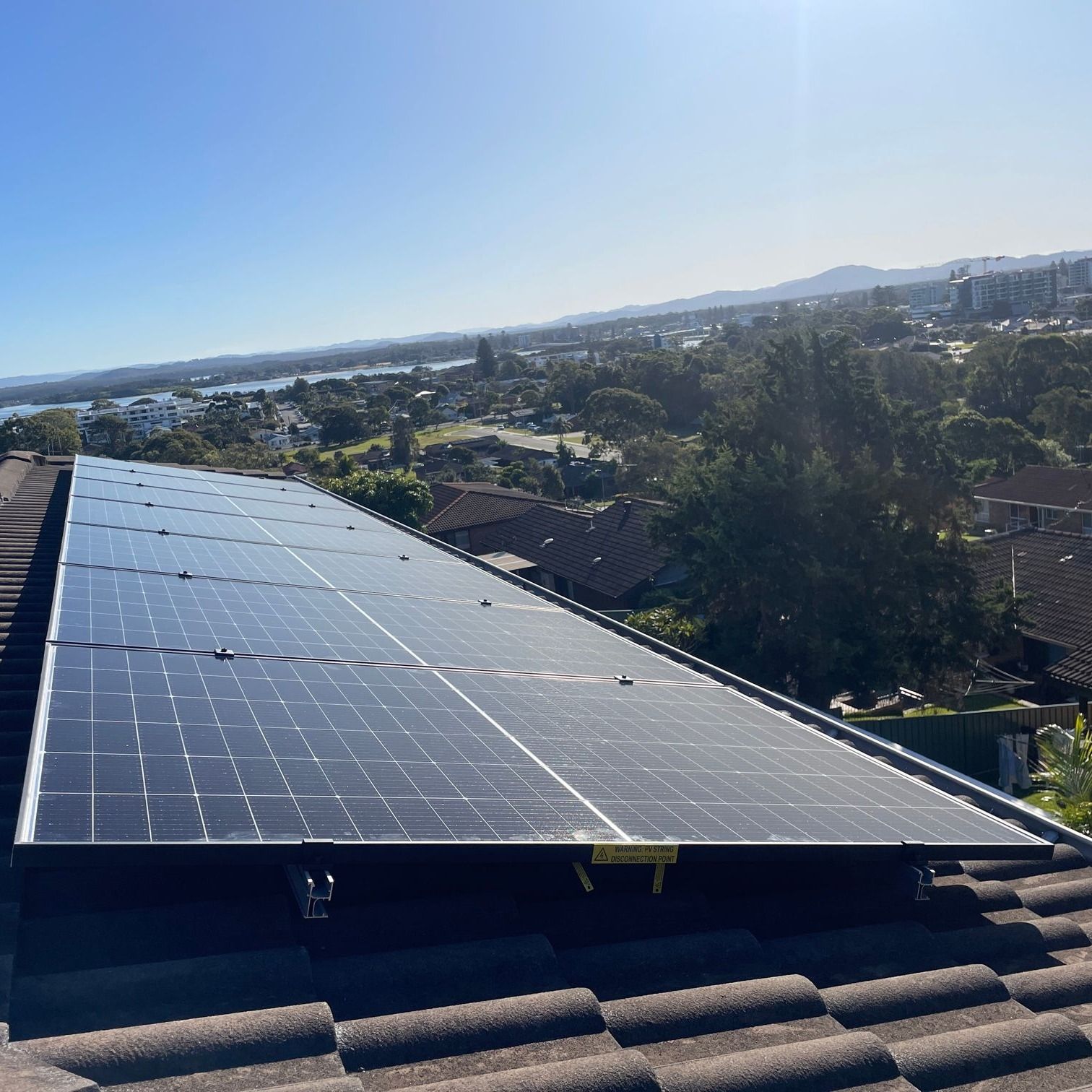 A Close up Of a Solar Panel with A Town in The Background   — Forster Solar and Lighting in Hallidays Point, NSW