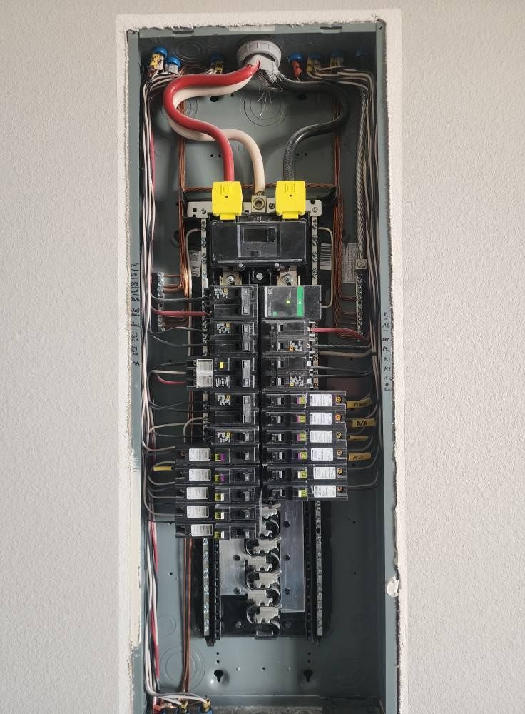 Open electrical panel with wires and circuit breakers.