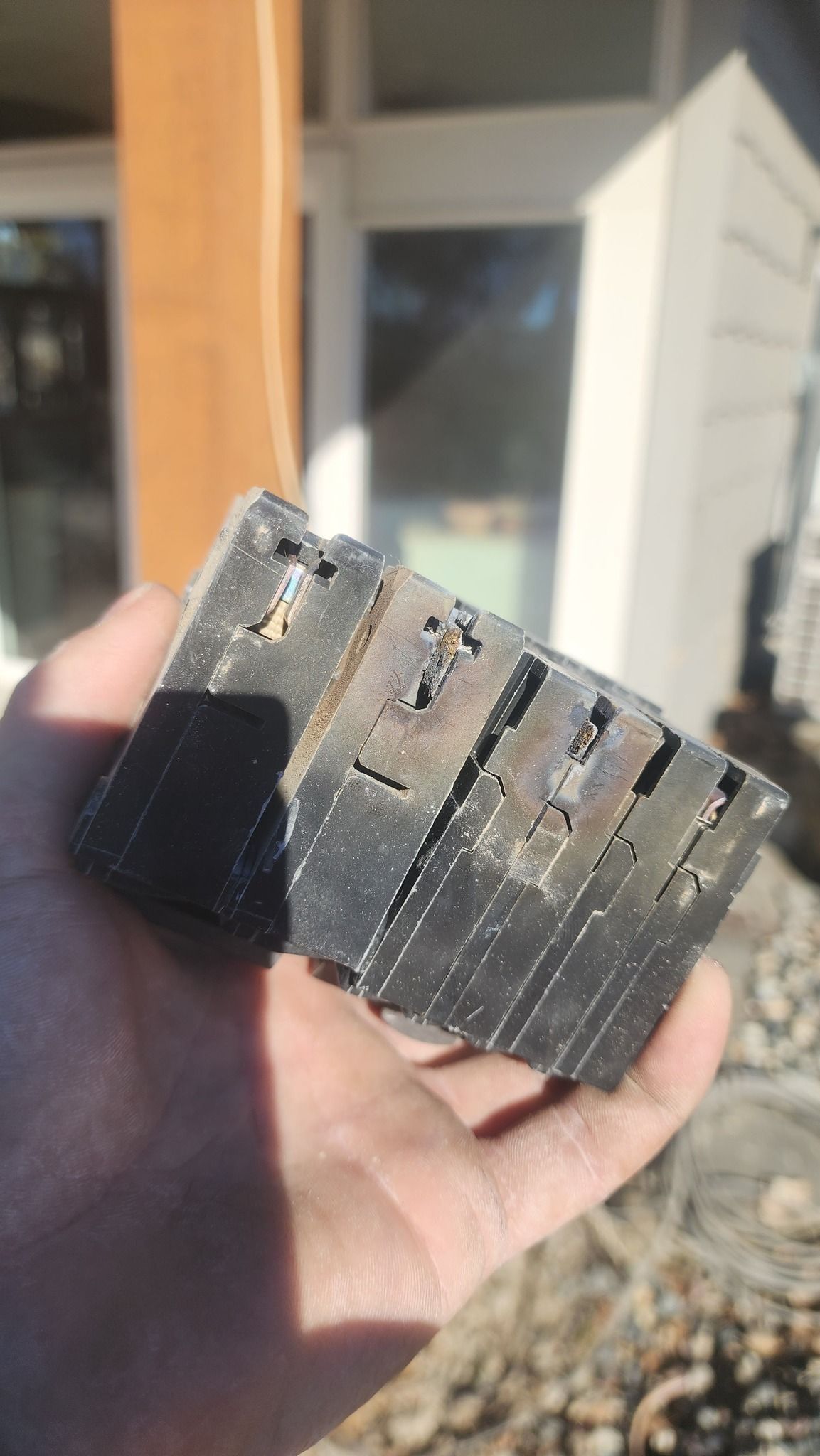 Hand holding a small, weathered rectangular object with layered, ridged sides.