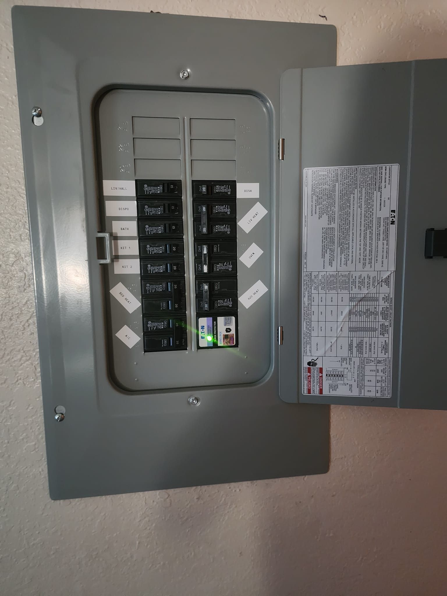 Gray electrical panel with open door, showing circuit breakers.
