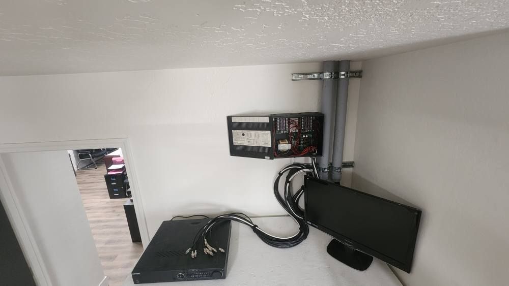 Electronics mounted on a white wall, including a monitor, server, and other equipment.