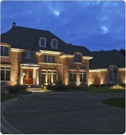 Brick house exterior at night, lit by spotlights; dark sky.
