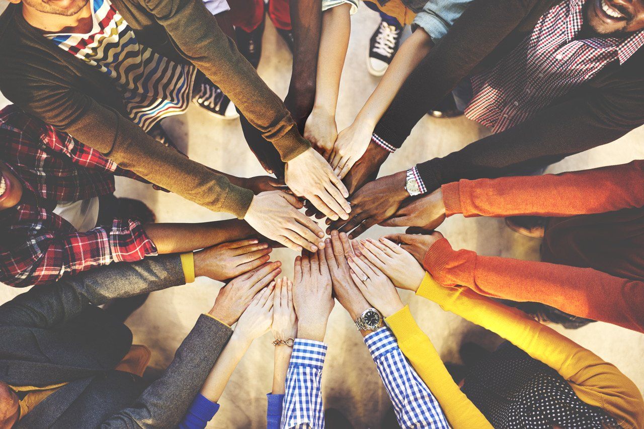 A group of people are putting their hands together in a circle.