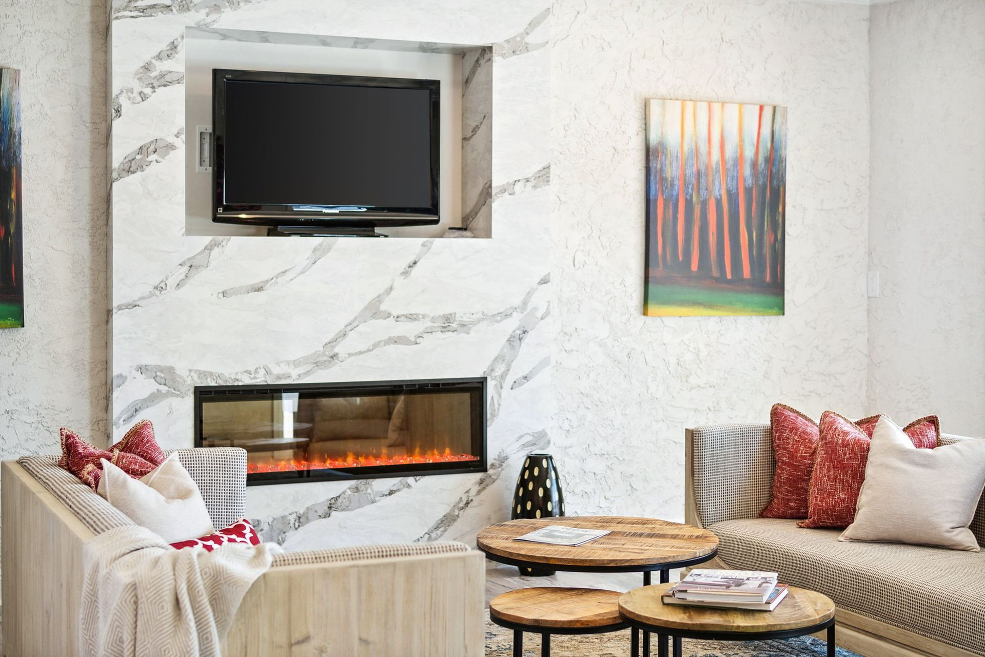 Living room with a fireplace, TV, and modern furniture. White walls, wood and marble accents.