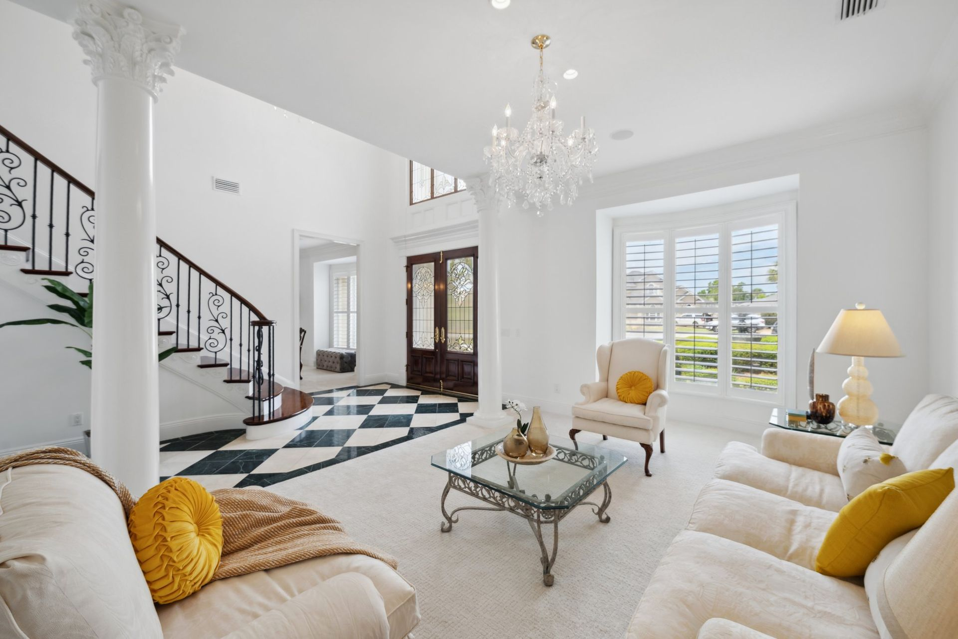 Elegant white living room with chandelier, black and white checkered floor, staircase.