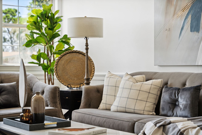Living room with gray sofa, lamp, plant, coffee table, and abstract art.
