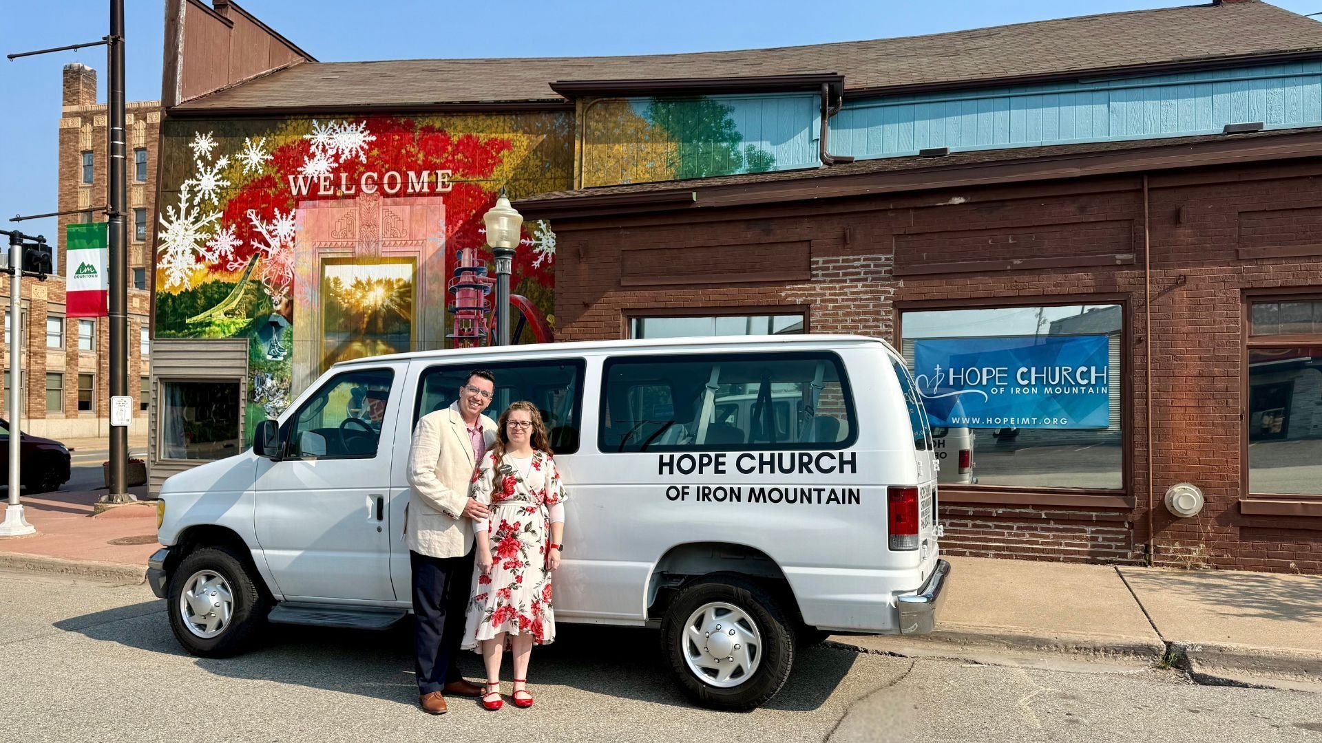 A man and woman are standing in front of a white van.