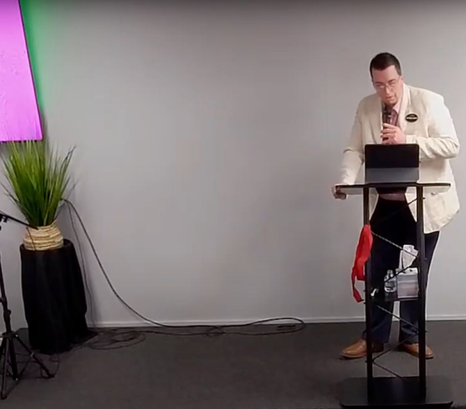 A man is standing at a podium talking into a microphone.