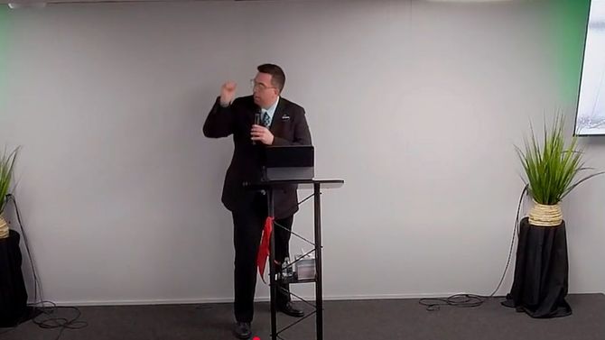 A man in a suit and tie is standing at a podium giving a speech.