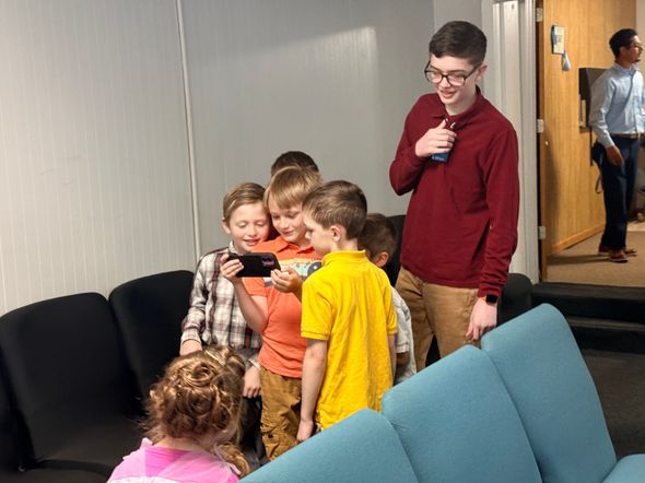 A woman in a white dress is talking to a group of people.