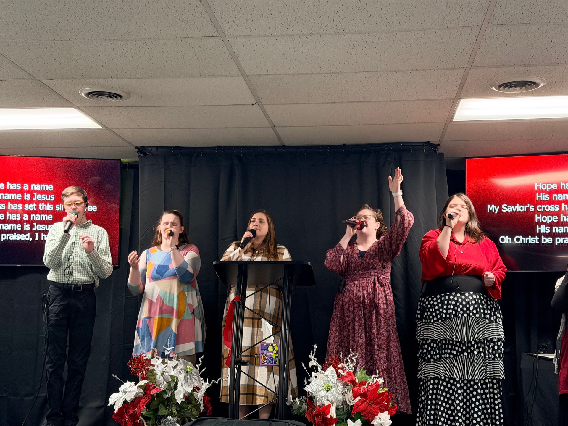 A group of people are sitting under a tent talking to each other.