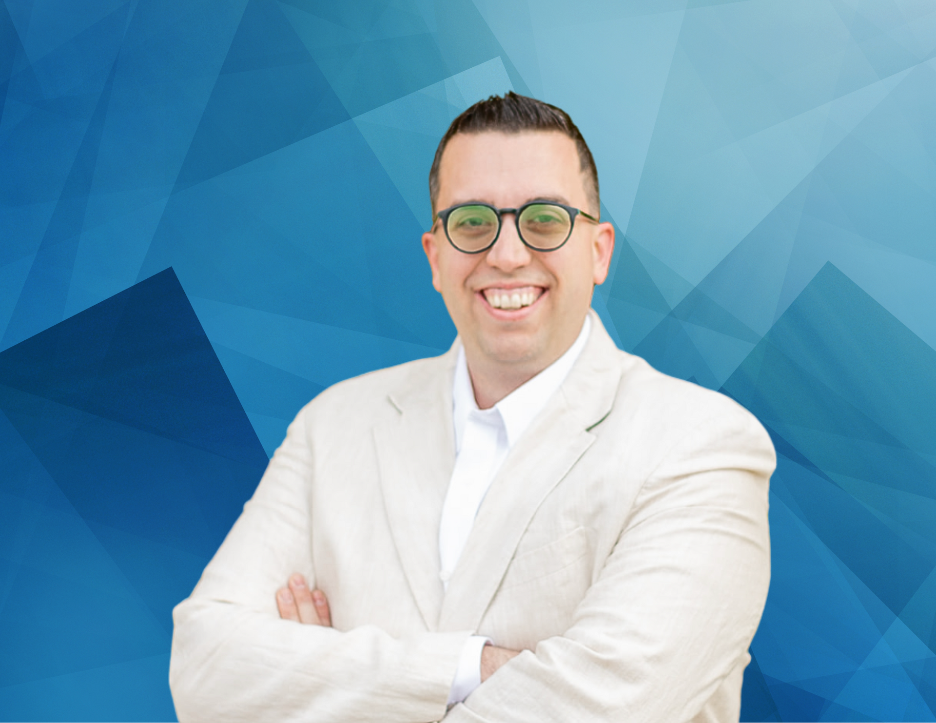 A man in a suit and glasses is smiling with his arms crossed.