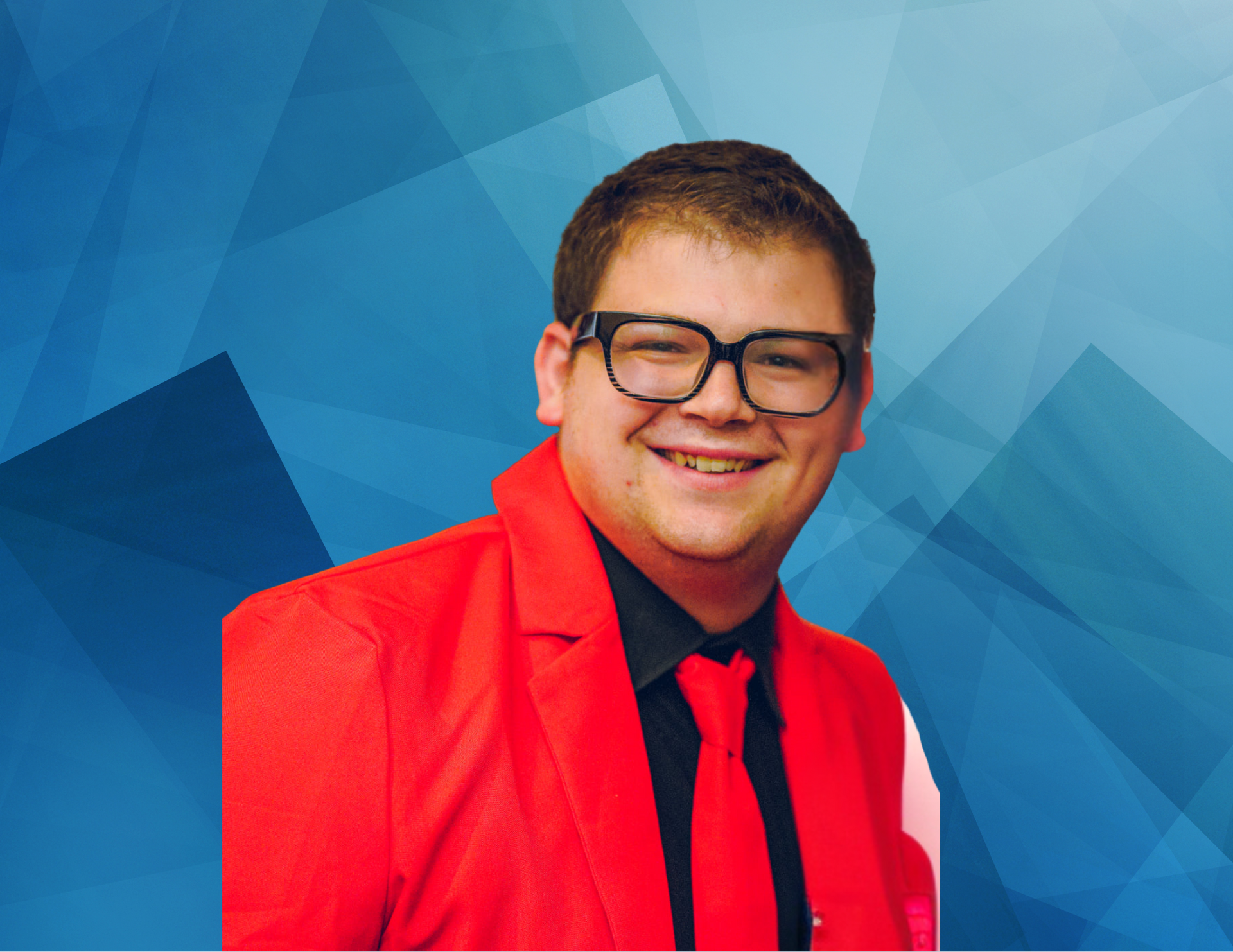 A young man wearing glasses and a red jacket and tie is smiling.